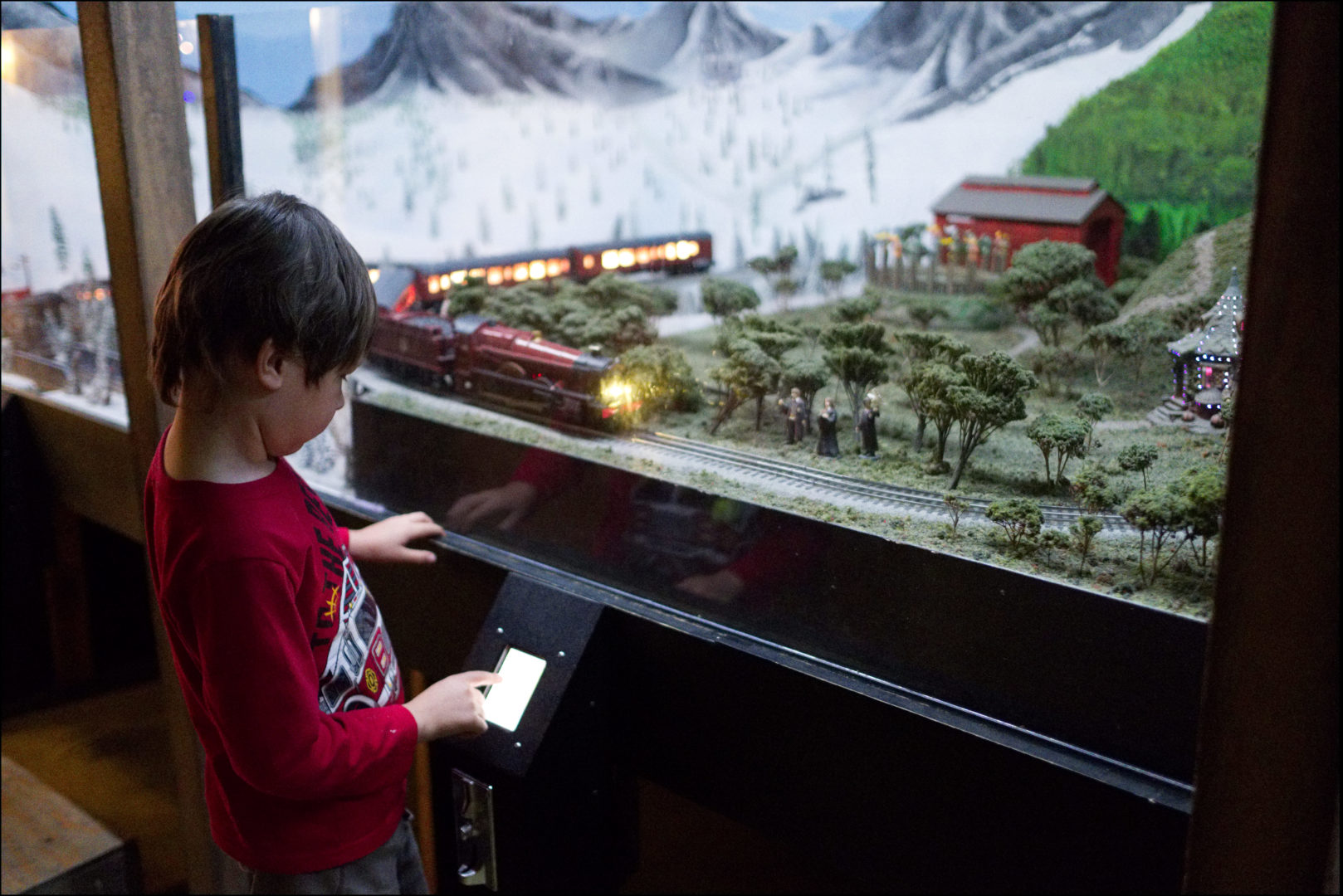 A little boy controls a model train set
