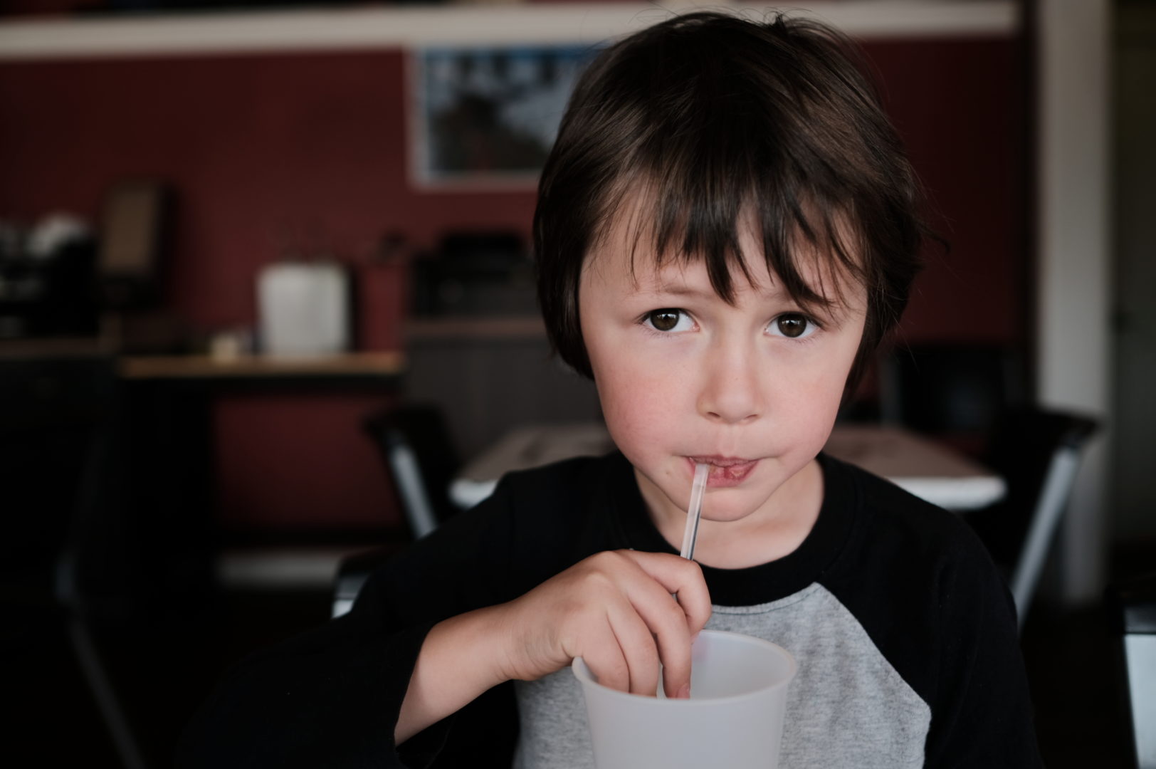 A little boy drinks through a straw.
