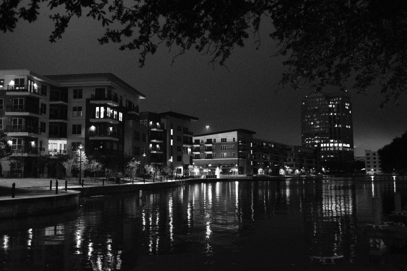 A B&W photo of a water way and Dallas in the dark.