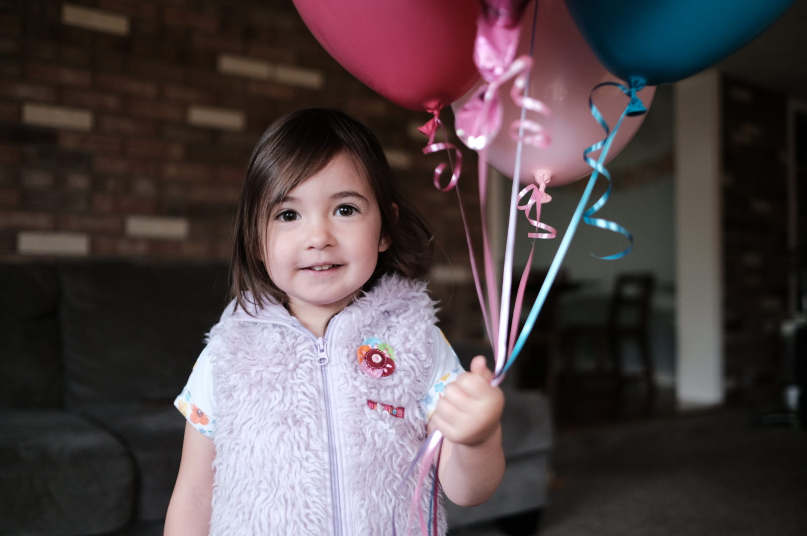 A little girl holds her birthday balloons