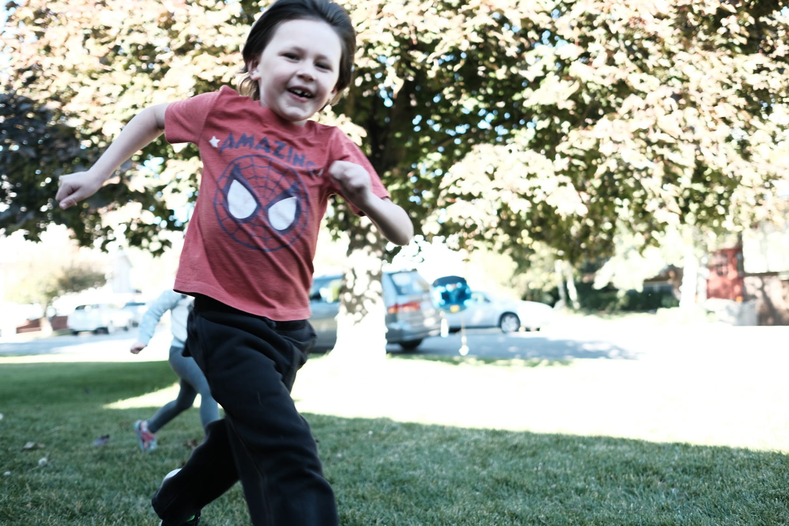 A smiling happy little boy runs past the camera