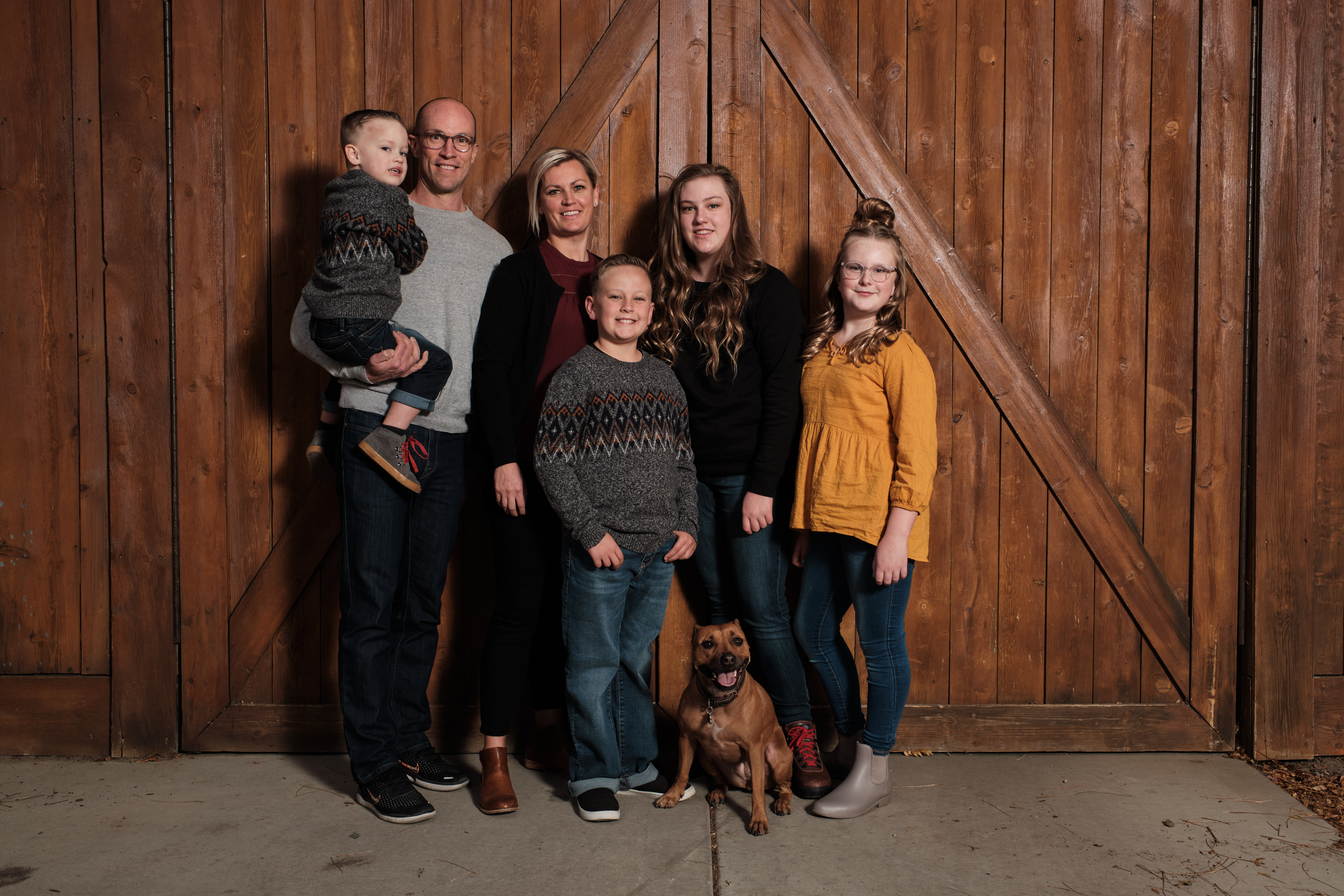 A family picture in front of a barn wall.